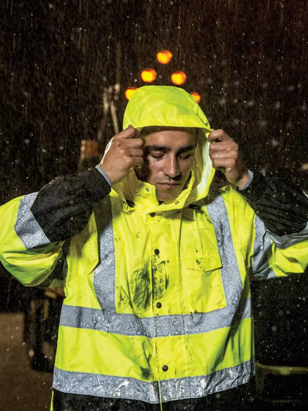 Worker wearing reflective safety rainwear in heavy rain
