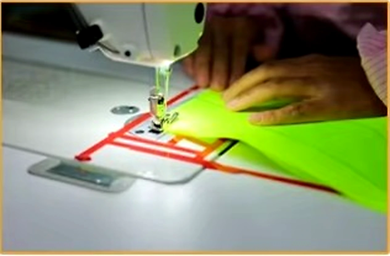 Edge binding being sewn onto fluorescent safety garment fabric