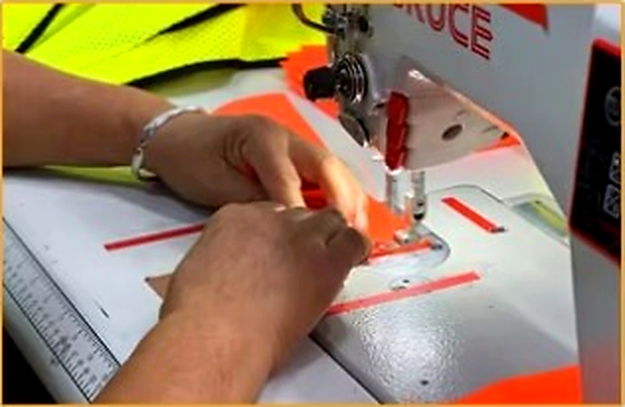 Reflective tape being sewn onto fluorescent workwear fabric