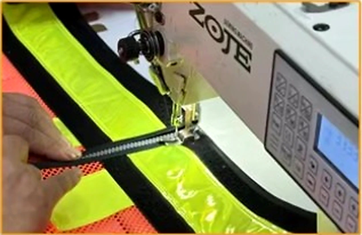Industrial sewing machine attaching a zipper to high visibility workwear